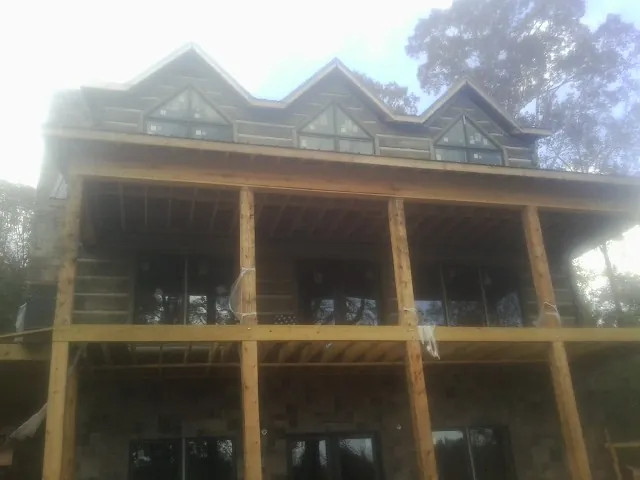 Dormers and porch framing on a large log home under construction — Roof Coating work by our crew in Grove