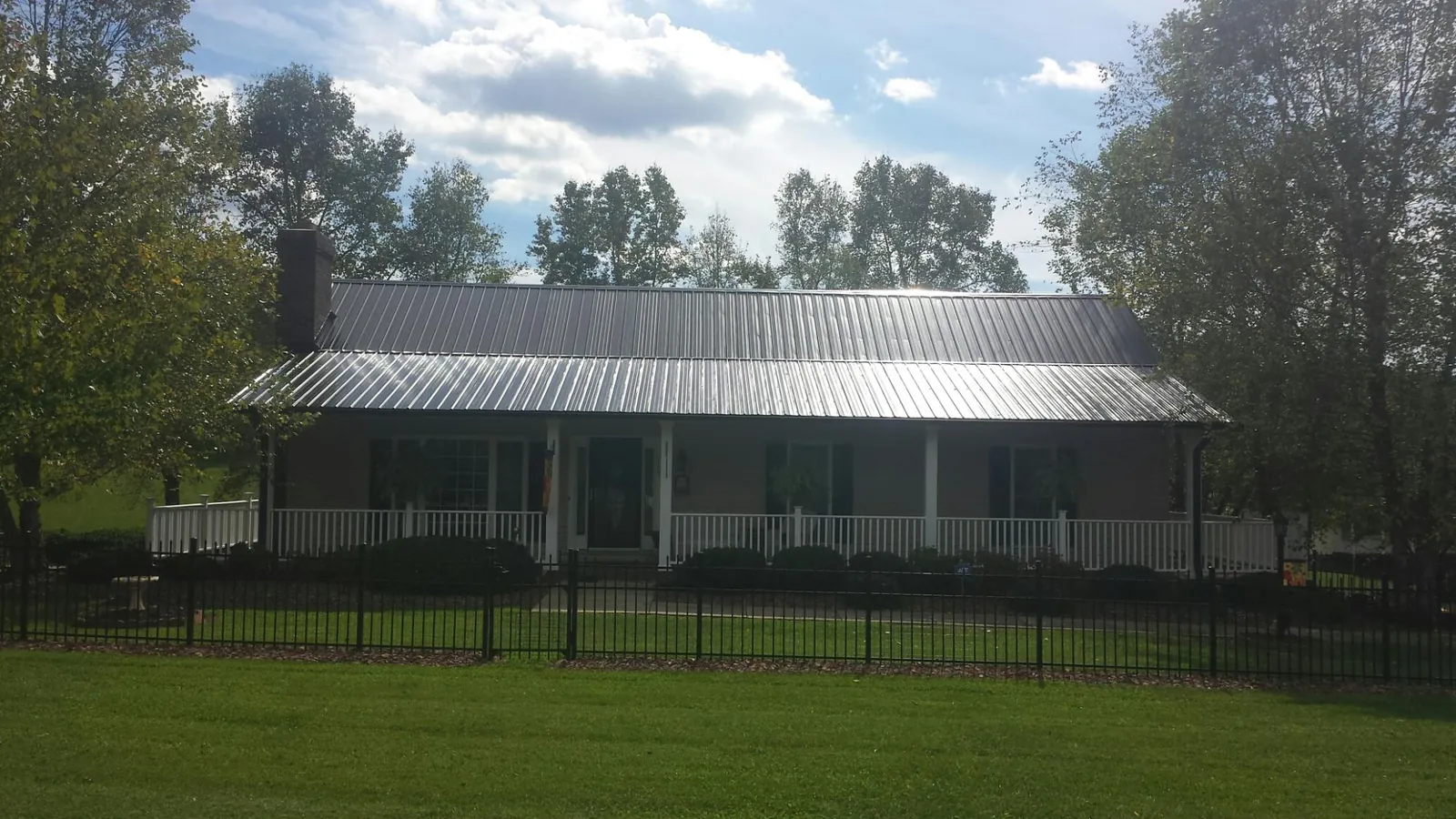 Gray metal roof on a brick ranch with a full width front porch — Gutter Guard Installation work by our crew in Grove