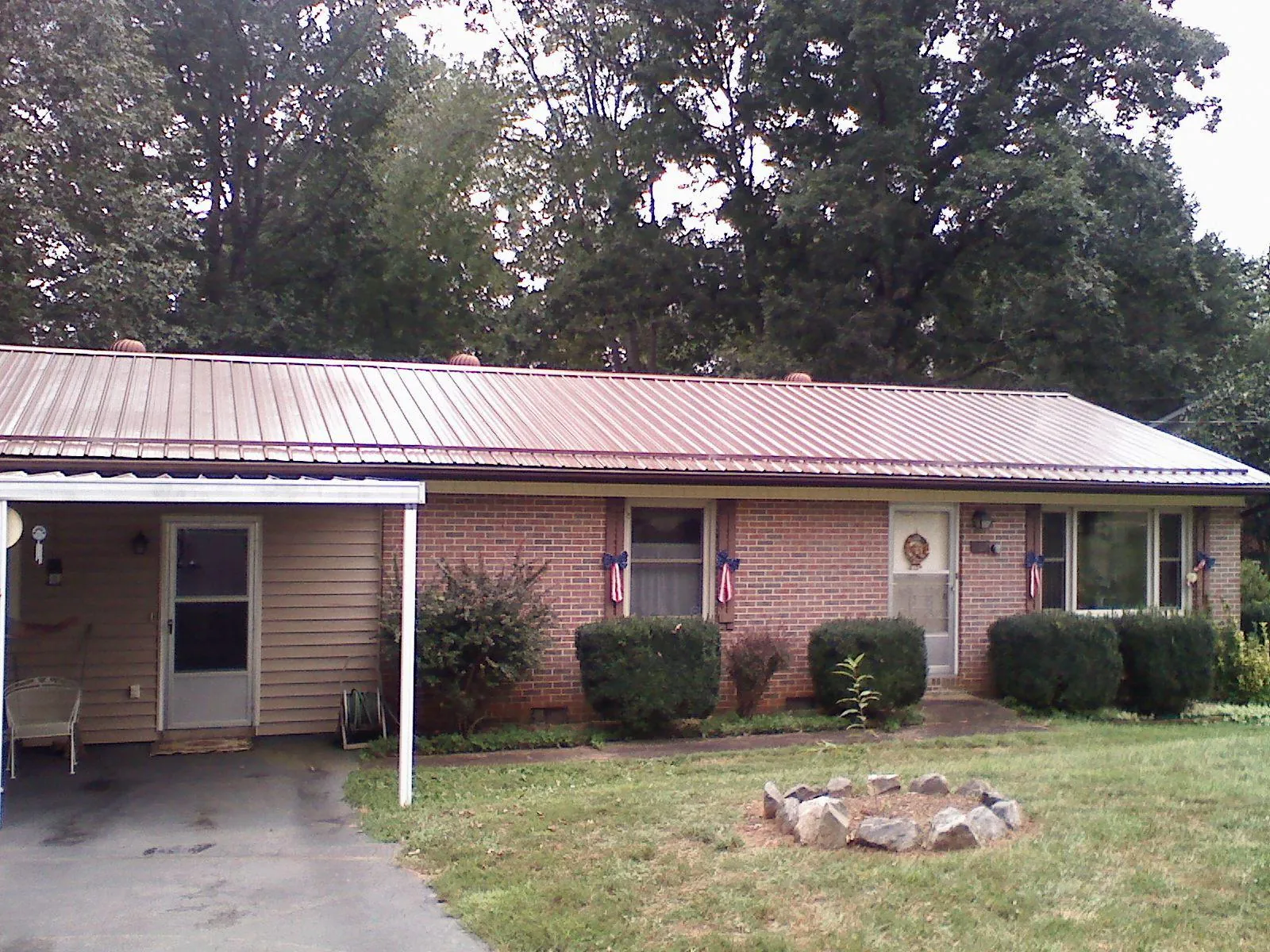 Bronze metal roof and carport on a brick ranch home — Roof Repair work by our crew in Grove