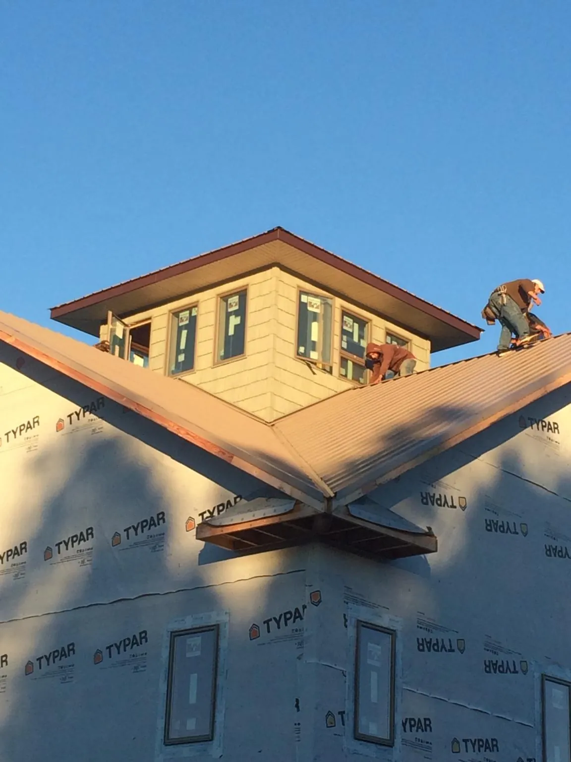 Roofers working around a rooftop cupola on a new metal roof at sunset — Roof Waterproofing in Grove by Roofing Brothers